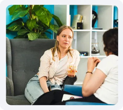 Two women sitting on couches having a conversation.