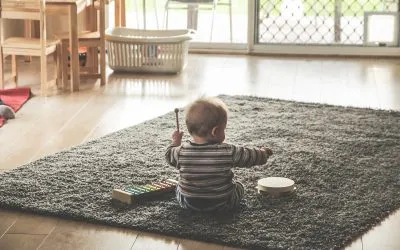 A baby playing with instruments on a carpet