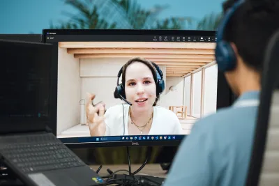 A man wearing headphones is in a video call with a woman wearing headphones.